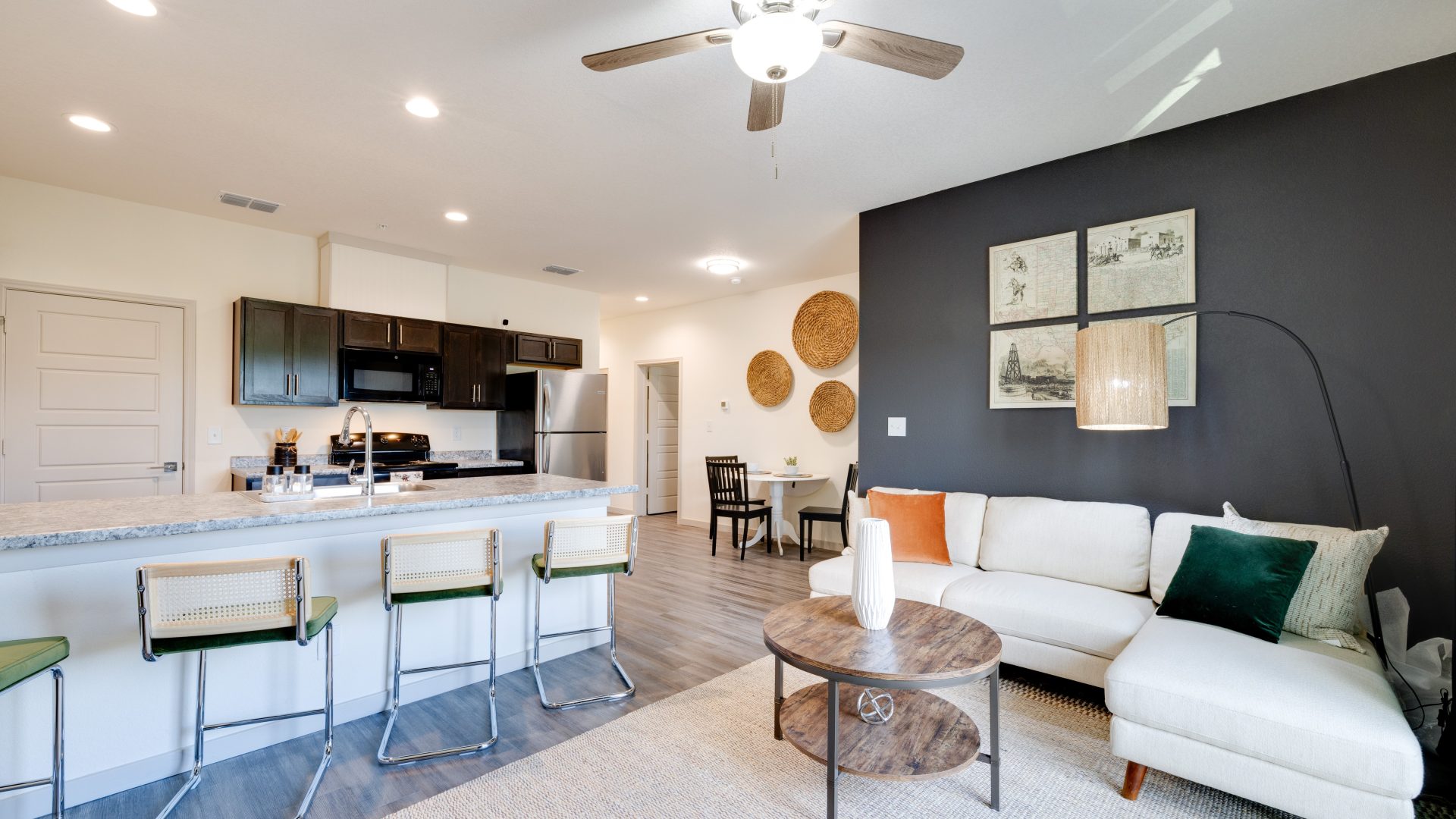 a living room and kitchen area with a ceiling fan at The Garden Creek Apartments
