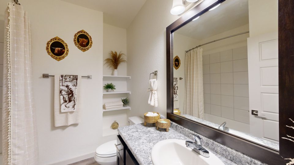 a bathroom with a sink, toilet and mirror at The Garden Creek Apartments